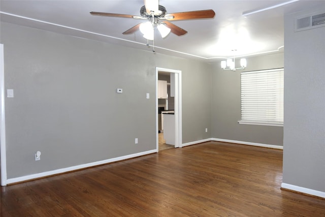 spare room featuring ceiling fan with notable chandelier, wood finished floors, visible vents, and baseboards