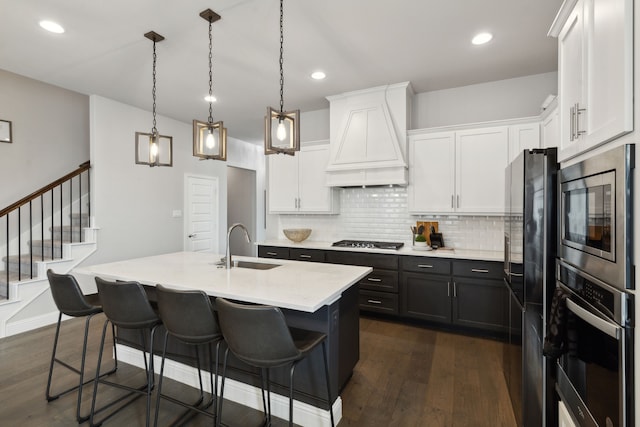 kitchen with premium range hood, appliances with stainless steel finishes, white cabinets, and decorative light fixtures