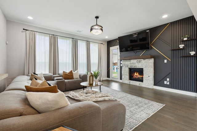 living area with a stone fireplace, dark wood-type flooring, recessed lighting, and baseboards