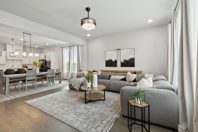 living room with dark wood-type flooring, recessed lighting, and a chandelier