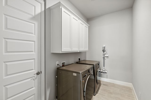 laundry area featuring cabinet space, baseboards, light wood-style floors, and washing machine and clothes dryer