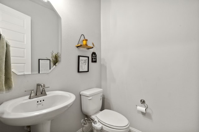 half bath featuring a sink, toilet, and baseboards