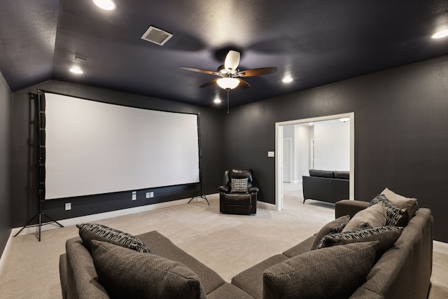 cinema room featuring lofted ceiling, light colored carpet, visible vents, ceiling fan, and baseboards