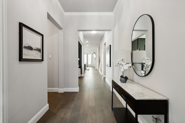 hall with dark wood-style flooring, crown molding, and baseboards