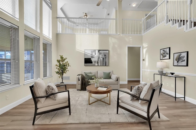 living area with visible vents, light wood finished floors, a ceiling fan, and baseboards