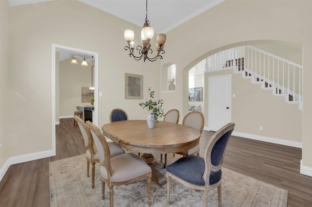 dining room with baseboards, arched walkways, dark wood-style floors, an inviting chandelier, and stairs