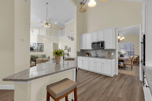 kitchen featuring light stone countertops, white cabinetry, stainless steel microwave, and a sink