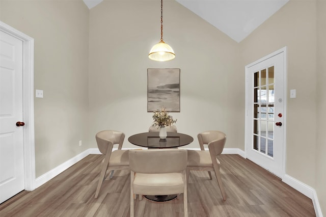 dining space featuring lofted ceiling, wood finished floors, and baseboards