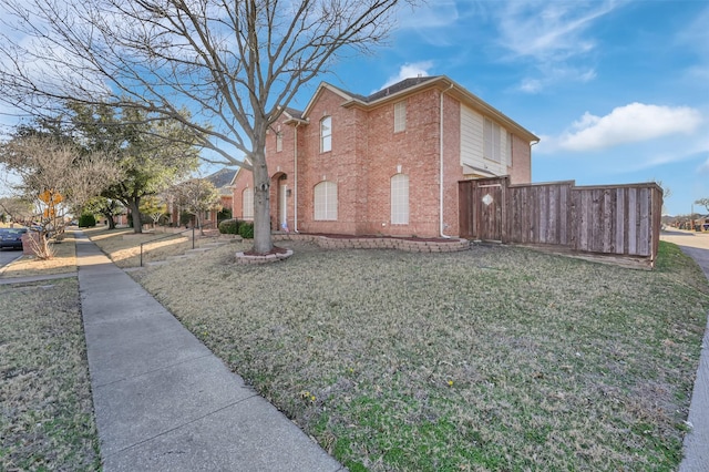 view of property exterior with brick siding, a yard, and fence