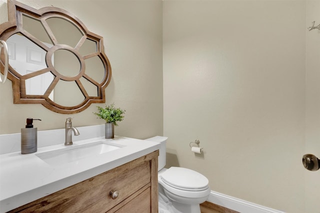 bathroom featuring baseboards, vanity, and toilet