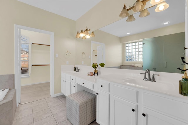 bathroom with a relaxing tiled tub, a sink, a spacious closet, tile patterned floors, and double vanity