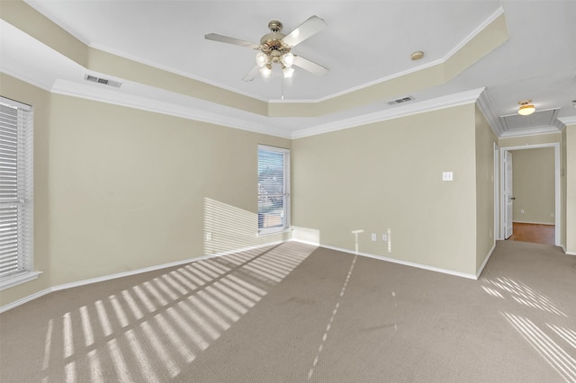 unfurnished room featuring ceiling fan, visible vents, baseboards, ornamental molding, and a tray ceiling