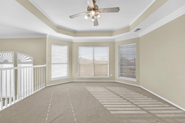 spare room featuring carpet floors, visible vents, a raised ceiling, and crown molding