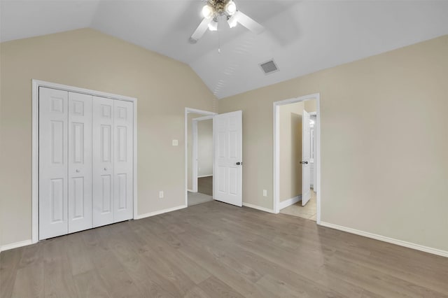 unfurnished bedroom with light wood finished floors, lofted ceiling, a closet, visible vents, and baseboards