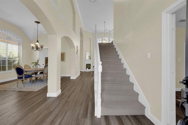 foyer entrance featuring stairs, baseboards, a fireplace, and dark wood-style flooring