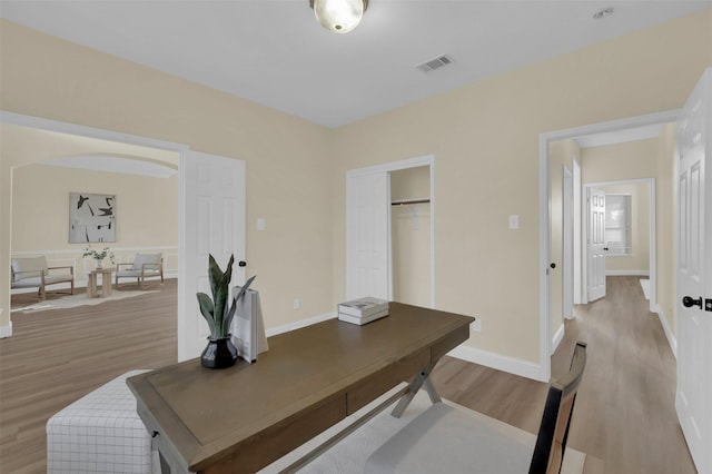 office with light wood-type flooring, baseboards, and visible vents