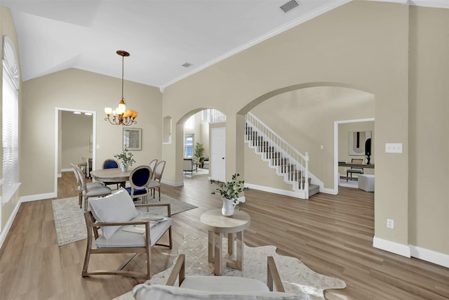 living area with arched walkways, plenty of natural light, wood finished floors, and visible vents