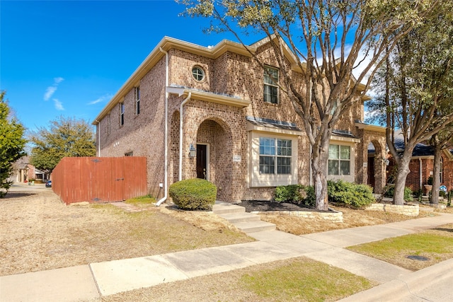 view of front facade with brick siding and fence