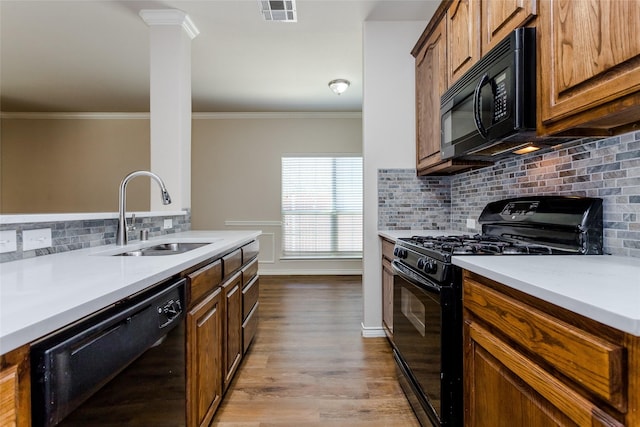 kitchen featuring a sink, visible vents, light countertops, black appliances, and brown cabinetry