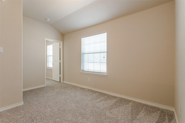 empty room featuring vaulted ceiling, light carpet, baseboards, and a healthy amount of sunlight