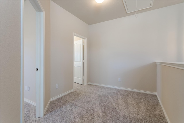 unfurnished room featuring attic access, light colored carpet, and baseboards