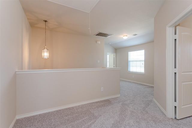 unfurnished room featuring visible vents, vaulted ceiling, light carpet, and baseboards