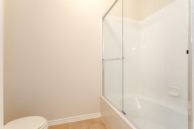 bathroom featuring toilet, enclosed tub / shower combo, baseboards, and tile patterned floors