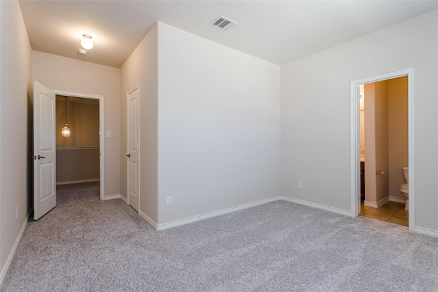 unfurnished bedroom with light colored carpet, ensuite bath, visible vents, and baseboards