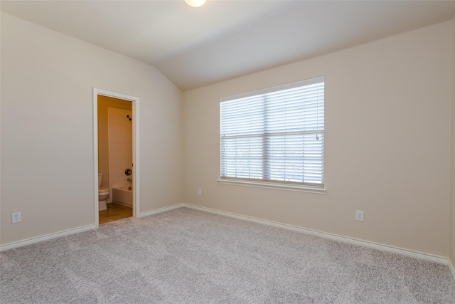 spare room featuring light carpet, baseboards, and vaulted ceiling