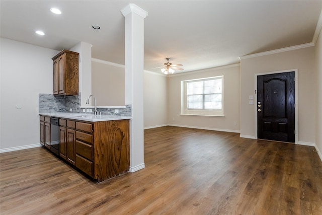 kitchen featuring light countertops, a sink, decorative backsplash, and wood finished floors