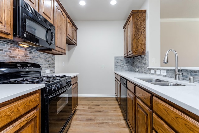 kitchen with a sink, black appliances, brown cabinetry, and light countertops