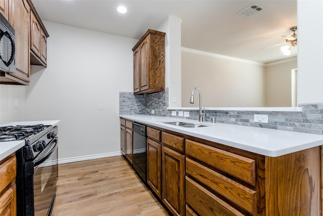 kitchen with a sink, black appliances, brown cabinetry, and light countertops