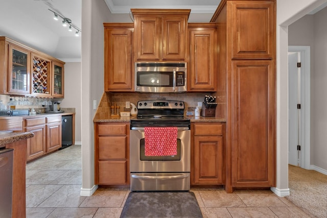 kitchen with decorative backsplash, glass insert cabinets, light stone countertops, stainless steel appliances, and crown molding