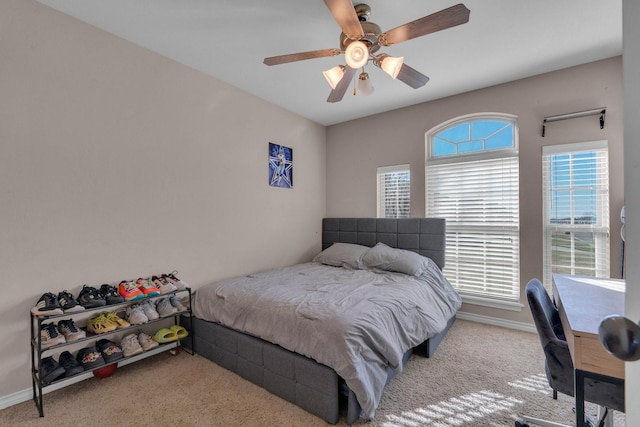 bedroom featuring multiple windows, ceiling fan, light carpet, and baseboards