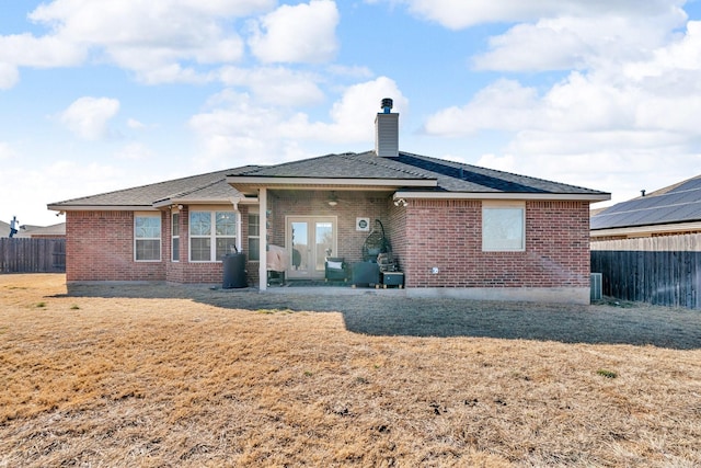 rear view of property with french doors, a chimney, fence, and brick siding