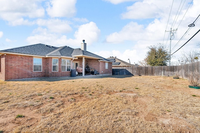 back of house featuring a chimney, brick siding, a fenced backyard, and roof with shingles