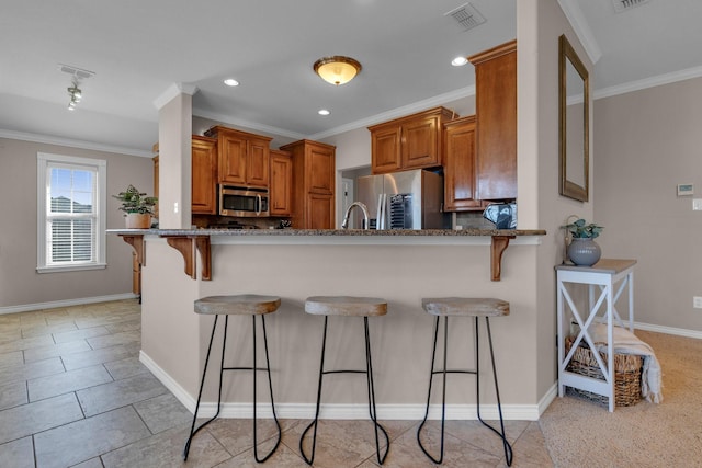 kitchen featuring appliances with stainless steel finishes, brown cabinets, a peninsula, and a kitchen breakfast bar