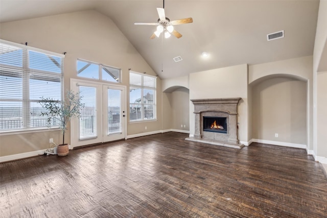 unfurnished living room with visible vents, arched walkways, ceiling fan, dark wood-type flooring, and a fireplace