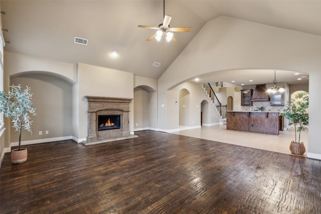 unfurnished living room with ceiling fan with notable chandelier, visible vents, dark wood finished floors, and a premium fireplace