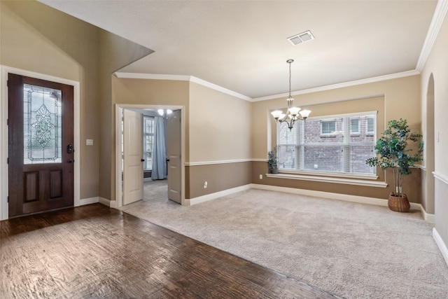 foyer featuring an inviting chandelier, baseboards, visible vents, and crown molding