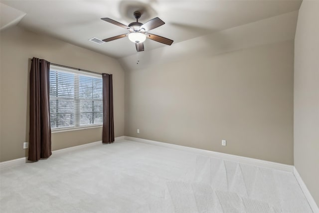 empty room with baseboards, visible vents, light colored carpet, lofted ceiling, and ceiling fan