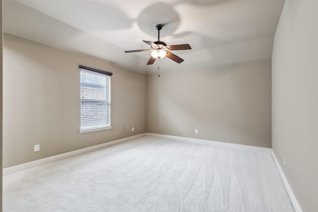 spare room featuring baseboards, a ceiling fan, and light colored carpet