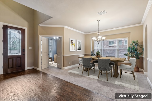 dining space with visible vents, ornamental molding, wood finished floors, a chandelier, and baseboards