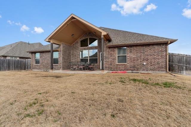 rear view of house with a yard, brick siding, and fence