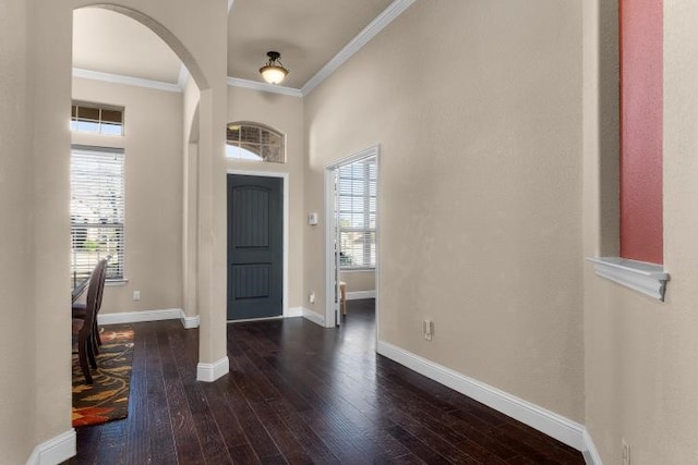 foyer with arched walkways, hardwood / wood-style floors, ornamental molding, and baseboards