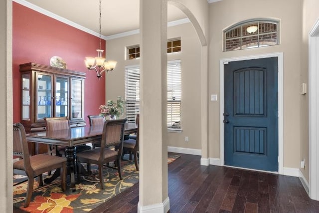 entryway featuring arched walkways, a notable chandelier, dark wood finished floors, ornamental molding, and baseboards