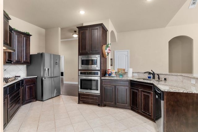 kitchen featuring stainless steel appliances, tasteful backsplash, a sink, and dark brown cabinets