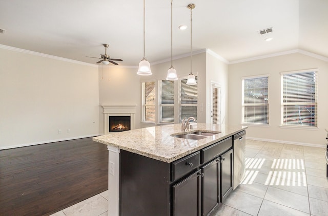 kitchen with visible vents, hanging light fixtures, open floor plan, a sink, and an island with sink