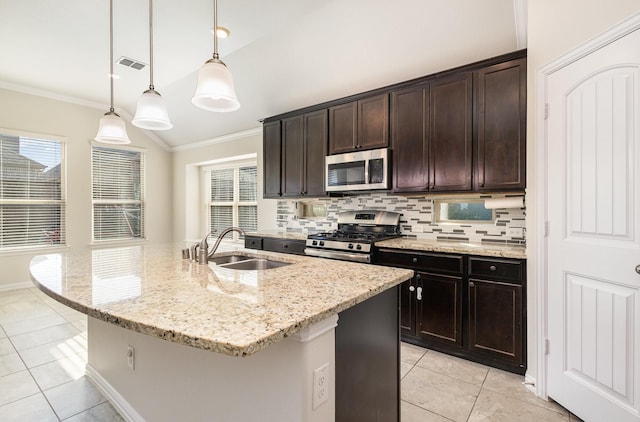 kitchen with dark brown cabinetry, appliances with stainless steel finishes, hanging light fixtures, a kitchen island with sink, and a sink