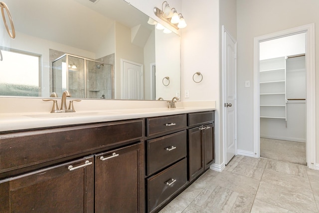 full bathroom featuring a sink, baseboards, a spacious closet, a shower stall, and double vanity